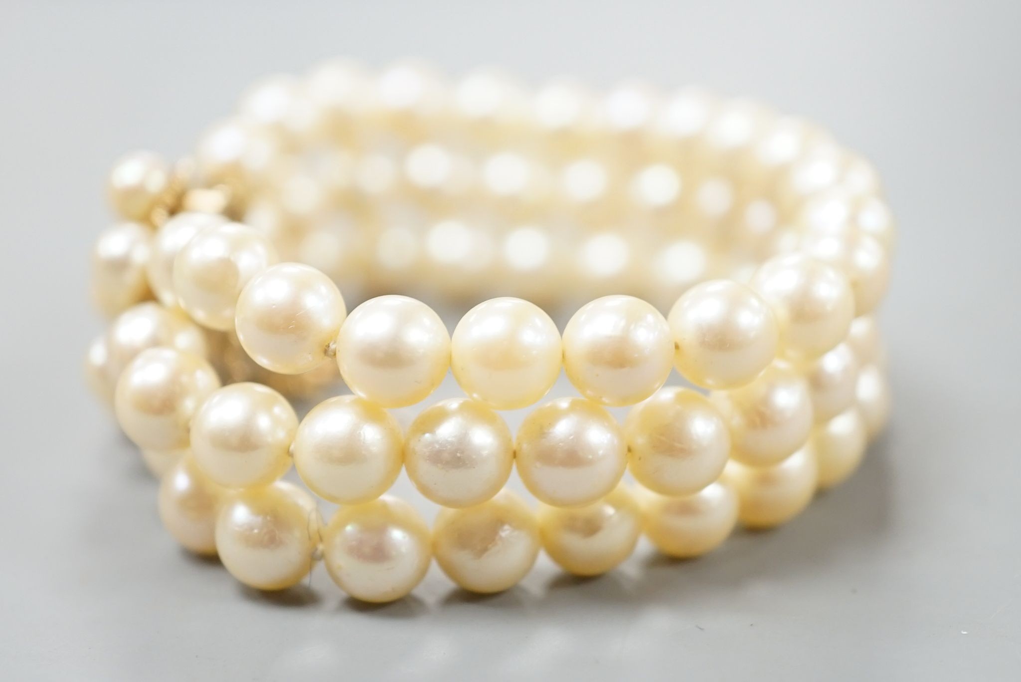 A triple strand cultured pearl bracelet, with yellow metal and cultured pearl cluster set clasp, approx. 16cm.